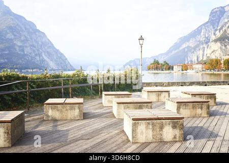 Bancs modernes dans le remblai par une journée ensoleillée près du lac italien de Côme. Banc extérieur en bois nature dans le style jardin zen. Amélioration de la ville, plan urbain Banque D'Images
