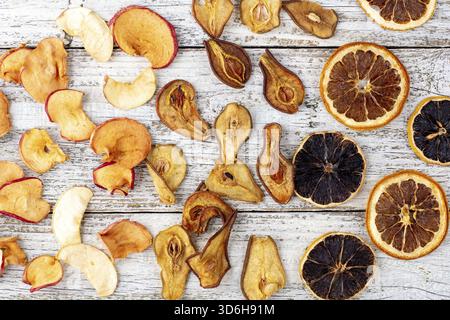 Nourriture, motif d'un tas de poires séchées agrumes et de pommes en tranches sur un fond de bois blanc. Chips de fruits séchés. Nourriture saine. Vue de dessus Banque D'Images