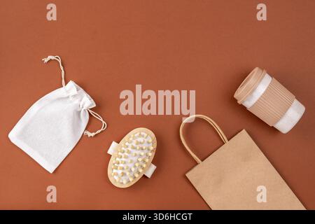 Ensemble d'articles réutilisables pour un style de vie respectueux de l'environnement. ECO coton et sac en papier, tasse à café, brosse à cheveux sur la surface brune. Zéro déchet, sans plastique Banque D'Images