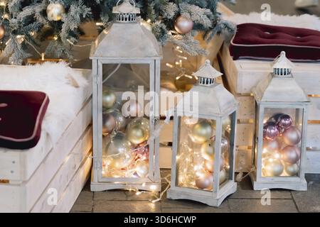 Lanterne avec boules de vacances sur fond d'arbre de noël décoré dans le salon intérieur. L'hiver et la lampe sur le canapé en bois près de l'arbre de noël. Banque D'Images