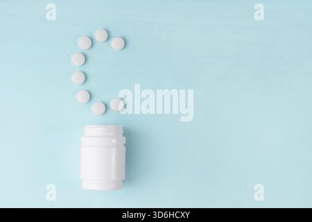 Les comprimés de vitamine C sont tombés du flacon sur le bleu. Lettre C des comprimés. Vitamine C concept. Concept de protection de l'immunité, prévention antivirale. Protection a Banque D'Images