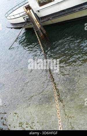 Lecco, Italie - 01.05.2023 : vue rapprochée des chaînes rouillées fixant le bateau amarré à la jetée, avec des eaux claires et calmes du lac ondulant doucement en dessous près de le Banque D'Images