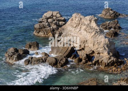 Vagues sur la plage rocheuse, rivage de la mer avec des vagues écrasant sur les grands rochers, journée ensoleillée d'été Banque D'Images