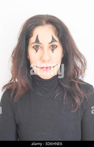 Femme au visage fait pour jouer un clown pour le Carnaval. La femme a trente-huit ans, a de longs cheveux noirs et porte un pull noir à col roulé Banque D'Images