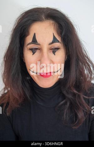 Belle femme de quarante ans avec du maquillage d'Halloween posant avec une expression intense sur un fond blanc Banque D'Images