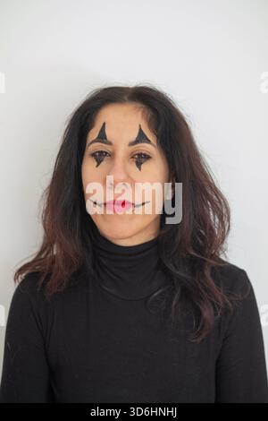 Belle femme de quarante ans avec du maquillage d'Halloween posant avec une expression intense sur un fond blanc Banque D'Images