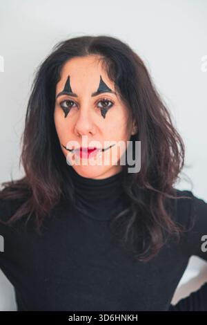 Belle femme de quarante ans avec du maquillage d'Halloween posant avec une expression intense sur un fond blanc Banque D'Images