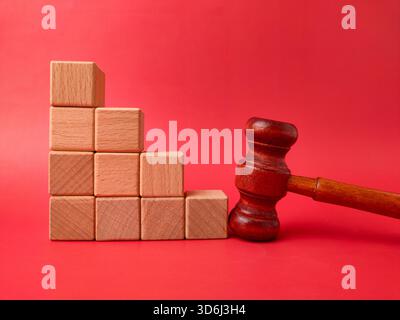L'image montre un marteau en bois à côté d'une pile de cubes en bois sur un fond rouge. Banque D'Images