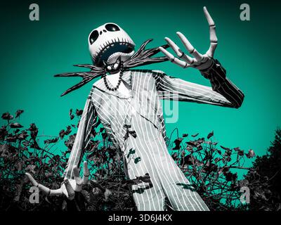 Vue en bas angle d'une sculpture de cour haute de Jack Skellington dans un costume rayé, tendue avec des mains squelettiques exagérées. Ciel sarcelle - effrayant et amusant. Banque D'Images