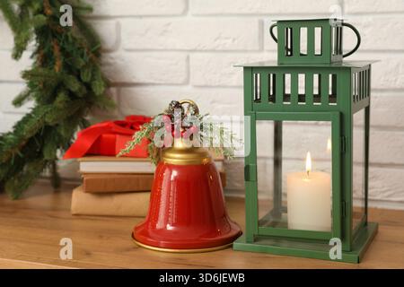 Couronne de Noël avec lanterne, boîte-cadeau, livres et cloche sur commode près du mur de briques blanches dans le salon Banque D'Images