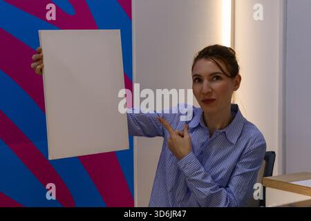 L'employé tient et pointe vers la feuille blanche dans l'environnement du bureau de livraison Banque D'Images