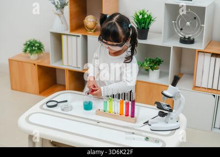 jeune fille scientifique faisant test chimique avec tube à essai et bécher. apprendre les sciences à la maison Banque D'Images