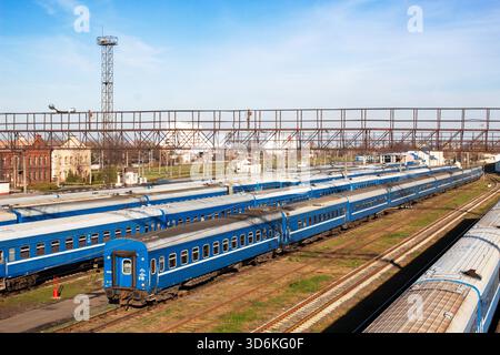 Vue aérienne de wagons bleus de train de voyageurs debout sur plusieurs voies ferrées à une gare de triage par une journée ensoleillée claire. Banque D'Images