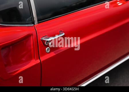 Poignée de porte de vieille voiture rouge. Poignée de porte chromée brillante du coupé classique - extérieur de muscle car des années 1960 Banque D'Images