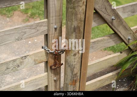 Chaîne rouillée fixant la porte de ferme en bois altéré Banque D'Images