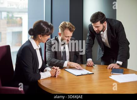 Des gens d'affaires concentrés discutant des documents pendant la réunion sur les décisions importantes de l'entreprise. Banque D'Images