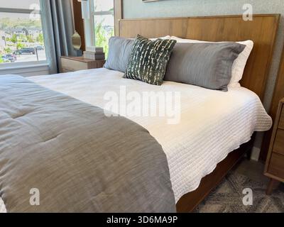 Gros plan du lit avec literie grise et blanche Banque D'Images