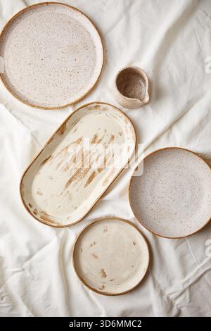 Assiettes en céramique et saucière sur un fond textile blanc. Céramiques faites à la main. Banque D'Images