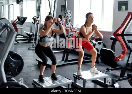 Deux femmes en sportswear sautant sur la plate-forme au gymnase Banque D'Images