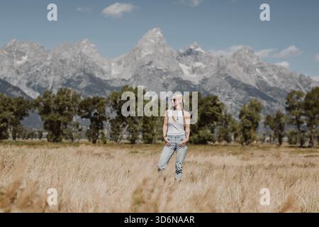 Belle femme dans le réservoir blanc se tient devant Tetons, Wyoming Banque D'Images