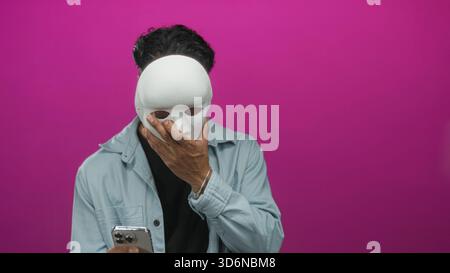 Jeune homme lisant un message sur l'écran de smartphone avec une expression sérieuse et une posture focalisée en studio ; concentration. Banque D'Images