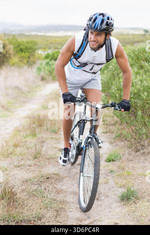 Homme chevauchant VTT avec des pneus Knobby le long de sentier de terre étroit portant casque pack d'hydratation. Cycliste, extérieur, accidenté, nature sauvage, exploration, a Banque D'Images
