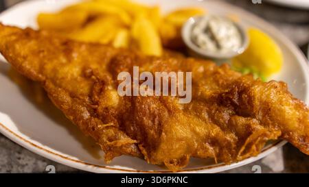 Poisson et frites dorés à la bière avec sauce tartare et pois pâteux. Cuisine de pub britannique classique, parfaitement cuisinée et magnifiquement présentée dans un tradit Banque D'Images