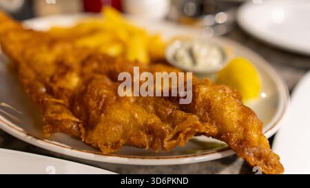 Poisson et frites dorés à la bière avec sauce tartare et pois pâteux. Cuisine de pub britannique classique, parfaitement cuisinée et magnifiquement présentée dans un tradit Banque D'Images