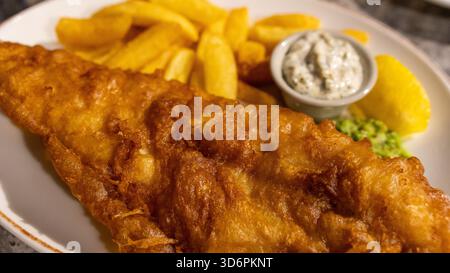 Poisson et frites dorés à la bière avec sauce tartare et pois pâteux. Cuisine de pub britannique classique, parfaitement cuisinée et magnifiquement présentée dans un tradit Banque D'Images