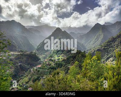 Vue idyllique sur les montagnes verdoyantes et brumeuses, route sinueuse et petit village. Paysage exotique de l'île de Madère, Portugal Banque D'Images