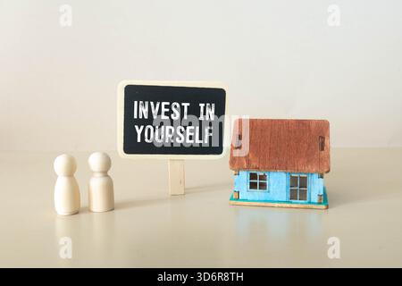Investissez dans votre symbole. Concept mots investissez en vous-même sur un bloc de bois sur une belle table orange fond orange. Main d'homme d'affaires. Entreprise Banque D'Images