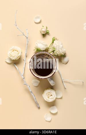 Tasse de café avec des fleurs de rose et des branches d'arbre sur fond beige Banque D'Images