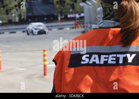 Agent de sécurité professionnelle femme dans un gilet orange montrant la vigilance. marshal féminin travaille sur la piste de course, assurant la protection et la sécurité pendant fas Banque D'Images