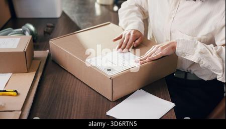 Mains, personne et étiquette de boîte pour le commerce électronique, les informations d'expédition et la distribution. Paquet, autocollant et femme dans la petite entreprise pour la livraison, priorité Banque D'Images
