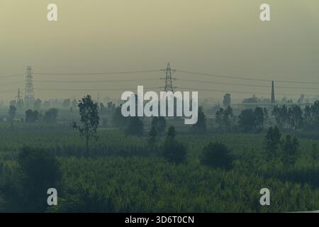 Larges terres agricoles avec des lignes électriques au-dessus d'un matin d'hiver brumeux près du village Haryana Inde Banque D'Images
