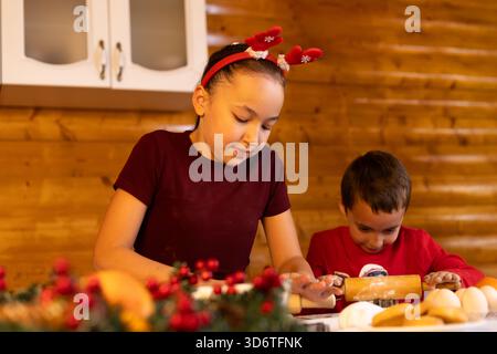 Les enfants cuisent des biscuits de Noël ensemble dans la cuisine Banque D'Images