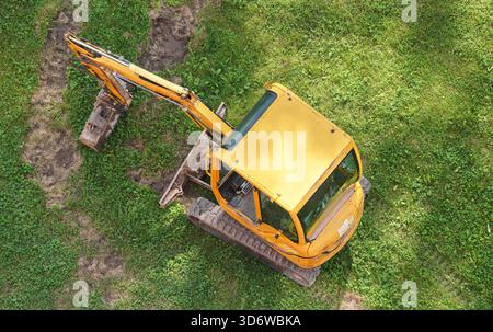 Petite pelle excavatrice, garée sur herbe verte, vue aérienne d'en haut Banque D'Images