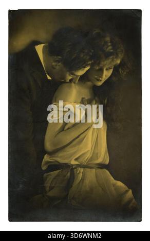 Une carte postale vintage aux tons sépia montre un homme embrassant tendrement l'épaule d'une femme, ses yeux baissés dans un moment d'affection intime. Banque D'Images