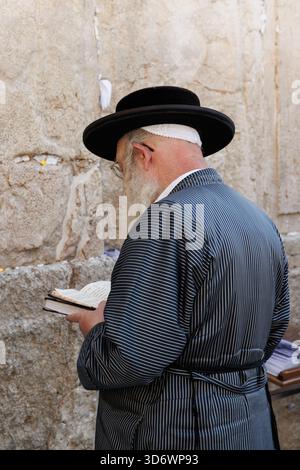 Israël, Jérusalem 23 octobre 2025 : adorateur juif orthodoxe debout dans la prière au mur Occidental à Jérusalem, vêtements traditionnels et chapeau, reli Banque D'Images