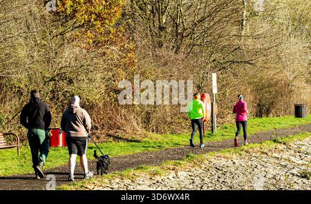 Dundee, Tayside, Écosse, Royaume-Uni. 22 novembre 2025. Météo britannique : les habitants apprécient le soleil éclatant de la fin de l'automne au Dundee Clatto Country Park, avec des eaux calmes reflétant les bois saisonniers. Crédit : Dundee Photographics/Alamy Live News Banque D'Images