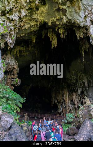 Touristes visitant une grande entrée de grotte au Pérou, entourée de formations rocheuses spectaculaires, stalactites et végétation naturelle luxuriante. Banque D'Images