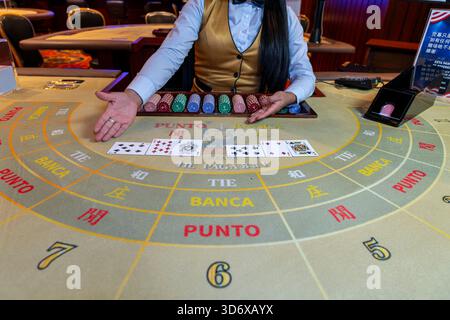 Table de baccarat présentant les cartes révélées, les mains du croupier, les jetons colorés et la disposition détaillée du casino capturée pendant l'atmosphère de jeu actif. Banque D'Images