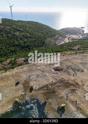 Vue aérienne de l'élimination des déchets sur le littoral avec des éoliennes sur la montagne. Banque D'Images