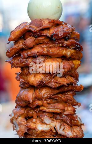Gros morceaux de viande sur une broche au marché alimentaire de rue en Thaïlande, gros plan. Brochettes de viande chiken crêpée à la broche. Restauration rapide. Banque D'Images