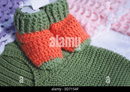 Chaussons de bébé tricotés à la main sur des tissus colorés Banque D'Images