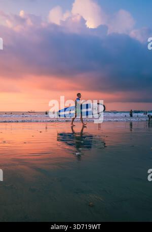 Les surfeurs se promènent tranquillement sur Jimbaran Beach dans l'après-midi du 5 octobre 2025, Bali, Indonésie Banque D'Images