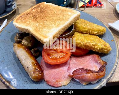 Un petit déjeuner anglais toute la journée avec bacon, saucisse, tomate, pommes de terre sautées, champignons dans un café. Banque D'Images