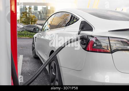 Voiture électrique à la station de charge rapide, EV blanc branché. Londres, Royaume-Uni, 14 octobre 2023 Banque D'Images