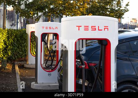 Stations Superchargeurs Tesla avec des VE branchés sur le parking. Londres, Royaume-Uni, 14 octobre 2023 Banque D'Images