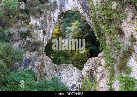 Fenêtre en arc de roche naturelle encadrant un canyon forestier caché à Corfou Grèce drone aérien vue rapprochée de la formation géologique de calcaire Banque D'Images